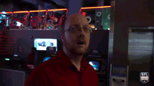 a man in a red shirt stands in front of a sign that says sanitizer station