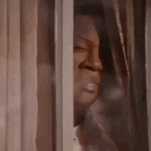 a man is looking out of a window with his eyes closed .