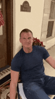 a man in a blue shirt is sitting on a chair in front of a door with a sign that says 1105