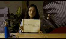a girl is holding a piece of paper that says # i am a victim