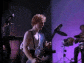 a man playing a guitar in front of a microphone
