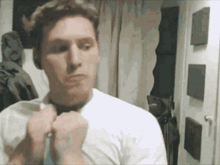 a man in a white shirt adjusts his tie