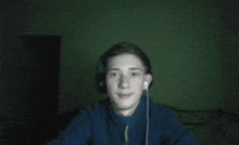 a young man wearing headphones looks at the camera while sitting in a dark room .