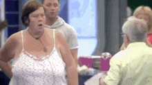 a woman in a white tank top is standing in front of a man in a green shirt .