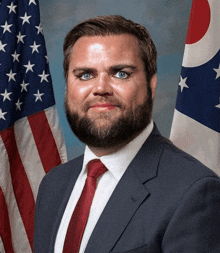 a man in a suit and tie stands in front of a flag