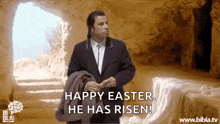 a man in a suit and tie is standing in front of a cave and says happy easter he has risen
