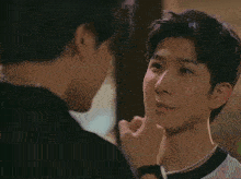 a man with a pearl necklace is covering his mouth with his finger