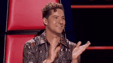 a man with curly hair is sitting in a chair with his hands in his pockets .