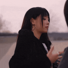 a woman wearing hoop earrings and a black jacket with the word fox on it