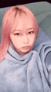 a girl with pink hair is wearing a blue sweatshirt