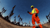 a man in orange overalls is giving a thumbs up