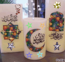 three candles decorated with arabic writing and stars