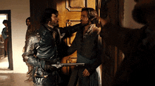 a man with a sword is standing next to another man with a gun