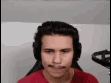 a man wearing headphones and a red shirt is sitting in a chair .