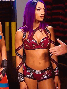 a female wrestler with purple hair is standing next to a man .