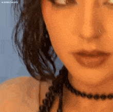a close up of a woman 's face with a nose ring and a choker necklace .