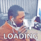 a man wearing headphones is holding a piece of paper in his mouth and says loading .