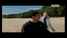 two men standing on a beach with a nickelodeon logo above them