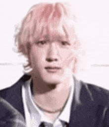 a man with pink hair is wearing a suit and tie and making a funny face .