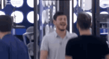 two men are standing next to each other in a room and one of them is laughing .