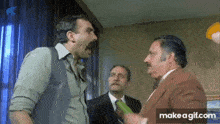 three men are standing in a room talking to each other .