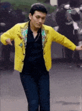a man wearing a yellow jacket and blue jeans is dancing