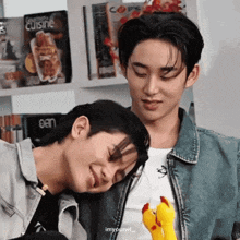 two young men are sitting next to each other with one holding a stuffed chicken