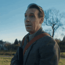 a man in a suit and tie stands in a field