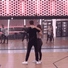 a man and woman are dancing in front of a mirror in a dance studio