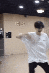 a man in a white t-shirt is dancing in a room .