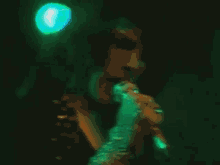 a man is singing into a microphone in a dark room with green lights .