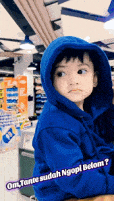 a little boy wearing a blue hoodie with the words om tante sudah ngopi belom written on it