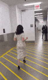 a woman in a white dress is running towards an exit