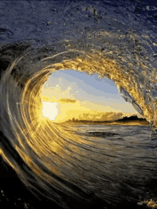 a wave is breaking on the beach and the sun is shining through it