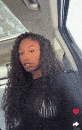 a woman with curly hair is sitting in a car