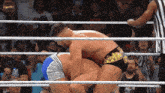 two men are wrestling in a ring with a referee standing behind them