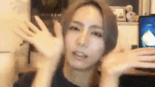 a woman is making a funny face with her hands in front of her face