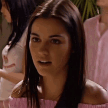 a woman in a pink off the shoulder top is looking at the camera .