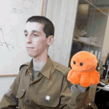 a man in a military uniform is holding a stuffed orange octopus