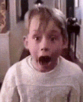 a young boy with his mouth open is wearing a white sweater and a hat .