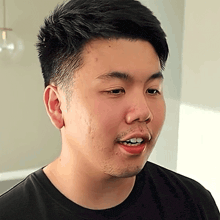 a man with a beard is wearing a black shirt and smiling