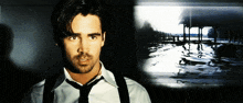 a man in a white shirt and black tie stands in front of a picture
