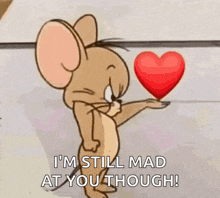 jerry from tom and jerry is holding a heart in his hand and says i 'm still mad at you though
