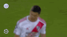 a soccer player in a white and red jersey is standing on the field .