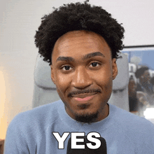 a man in a blue sweater is smiling and says yes