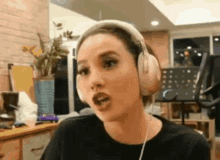 a woman wearing headphones is making a funny face while sitting at a table .
