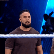 a man with a beard is standing in a wrestling ring looking at the camera