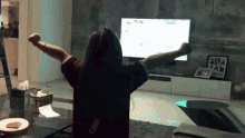 a woman sitting in front of a tv with her arms outstretched