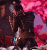 a man is covering his face with his hands in front of a pink background