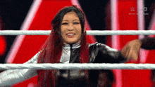 a woman with long red hair is standing in a wrestling ring .